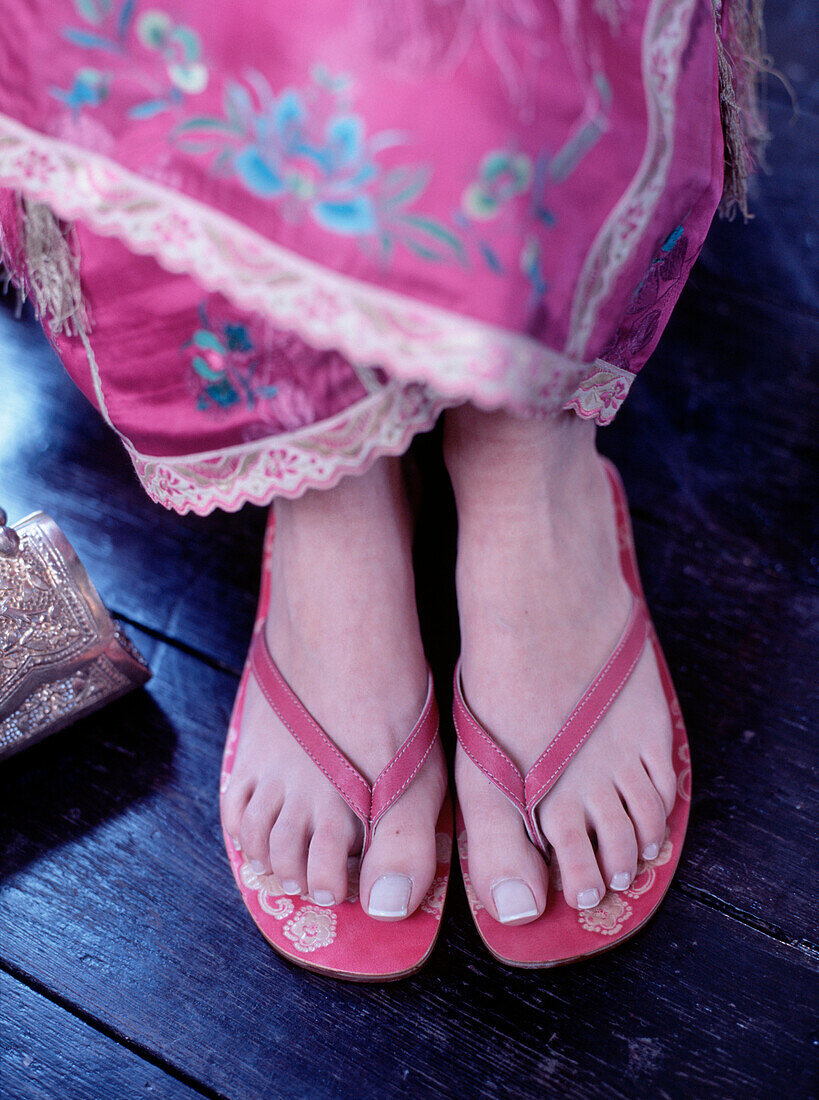 Frau in orientalischem Kleid und Nahaufnahme von Füßen in Flip Flops