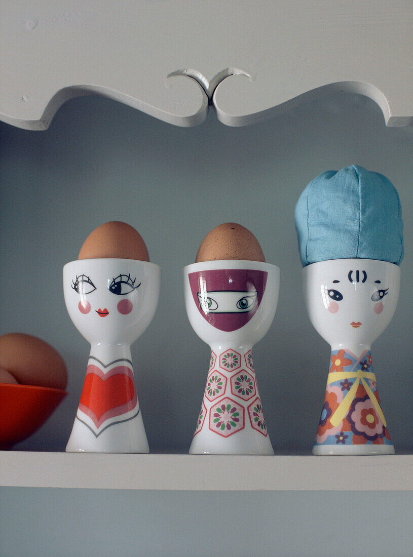 three eggs cups in a row on a shelf