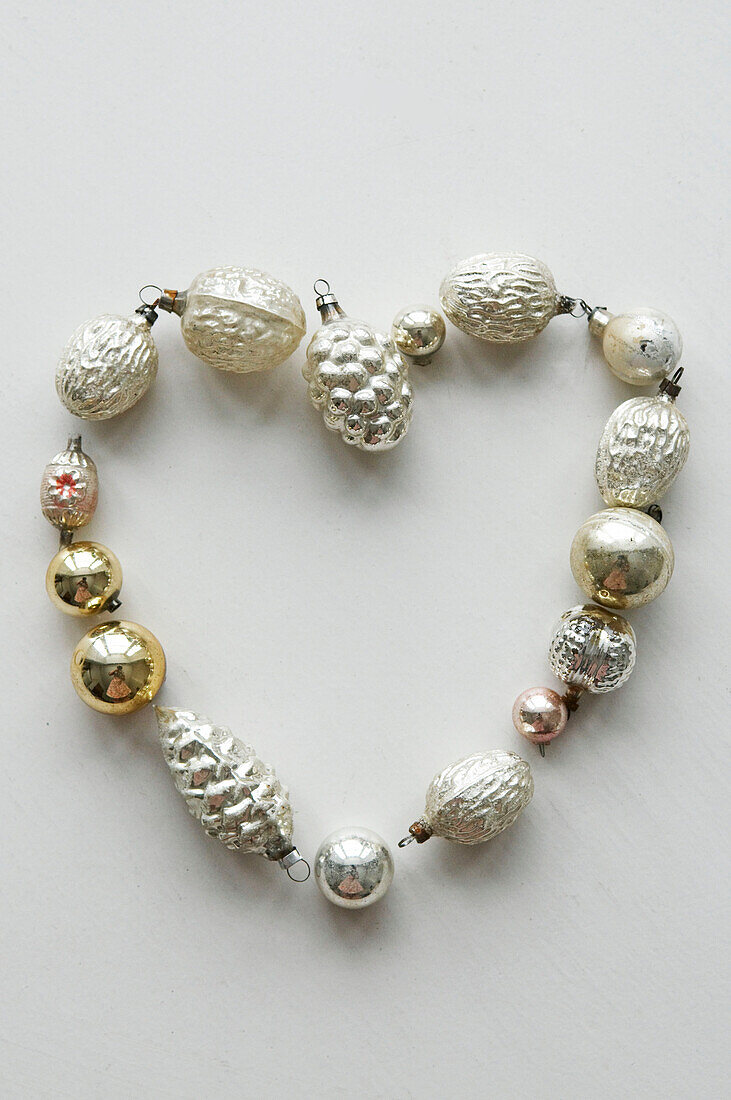 group of metallic christmas baubles arranged in a heart shaped symbol