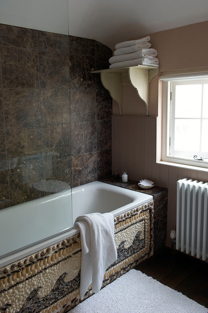 Braunes und cremefarbenes Badezimmer mit Muschelmuster an der Seite der Badewanne