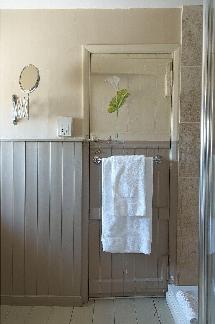 Braun- und cremefarbenes Badezimmer mit Nut- und Federverkleidung und Lilie an der Tür