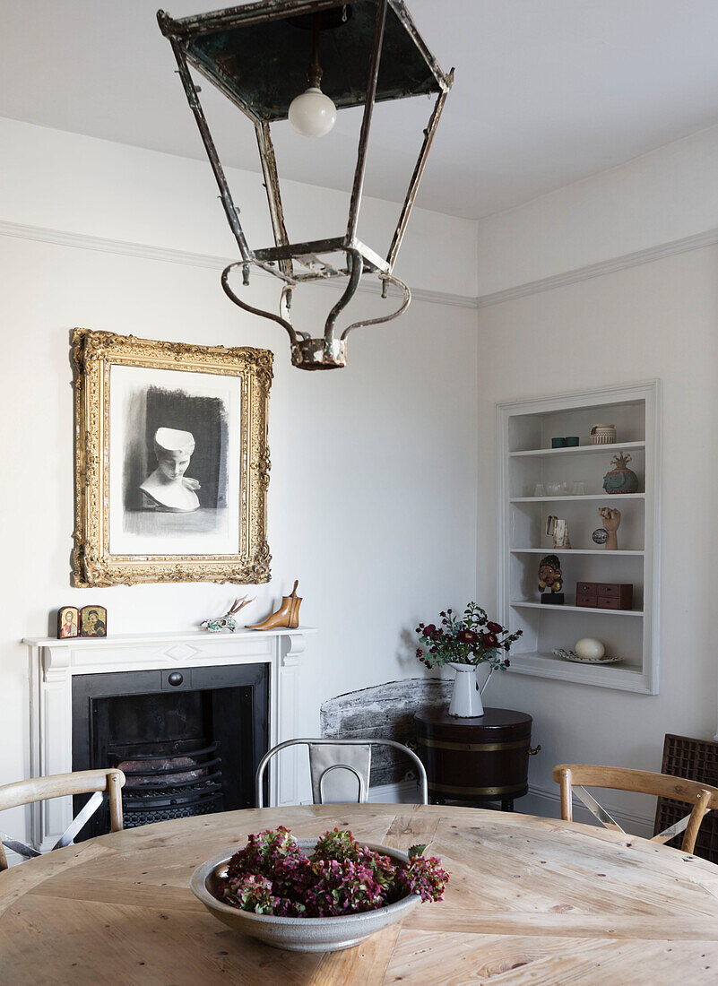Vintage lantern above wooden table with gilt framed print in Somerset home UK