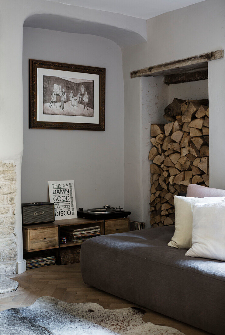 Brennholzlager und Plattenspieler mit niedriger Sitzgelegenheit in einem Haus in Somerset, UK