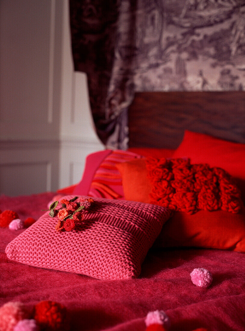 Doppelbett im Schlafzimmer mit farbenfroher Bettdecke, Kissen und strukturierten Polstern