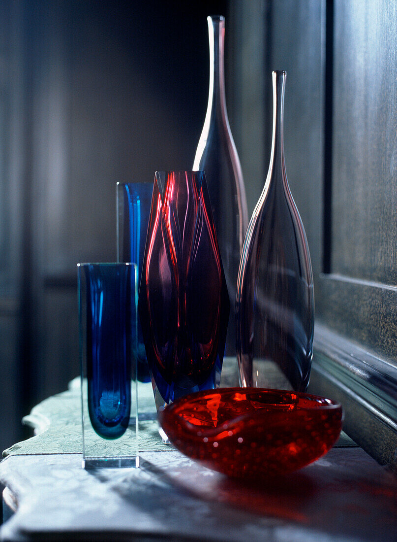 Auslage von bunten Glasvasen, Schalen und Flaschen auf einer Kommode im Wohnzimmer