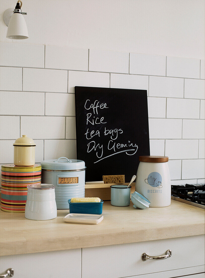 Kitchen side board with shopping list written on blackboard and kitchen storage containers displayed