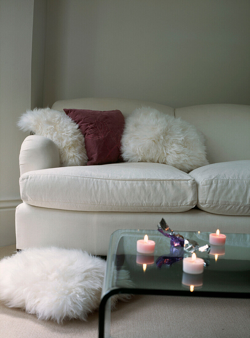 Weißes bequemes Sofa in weißem Wohnzimmer mit gläsernem Couchtisch
