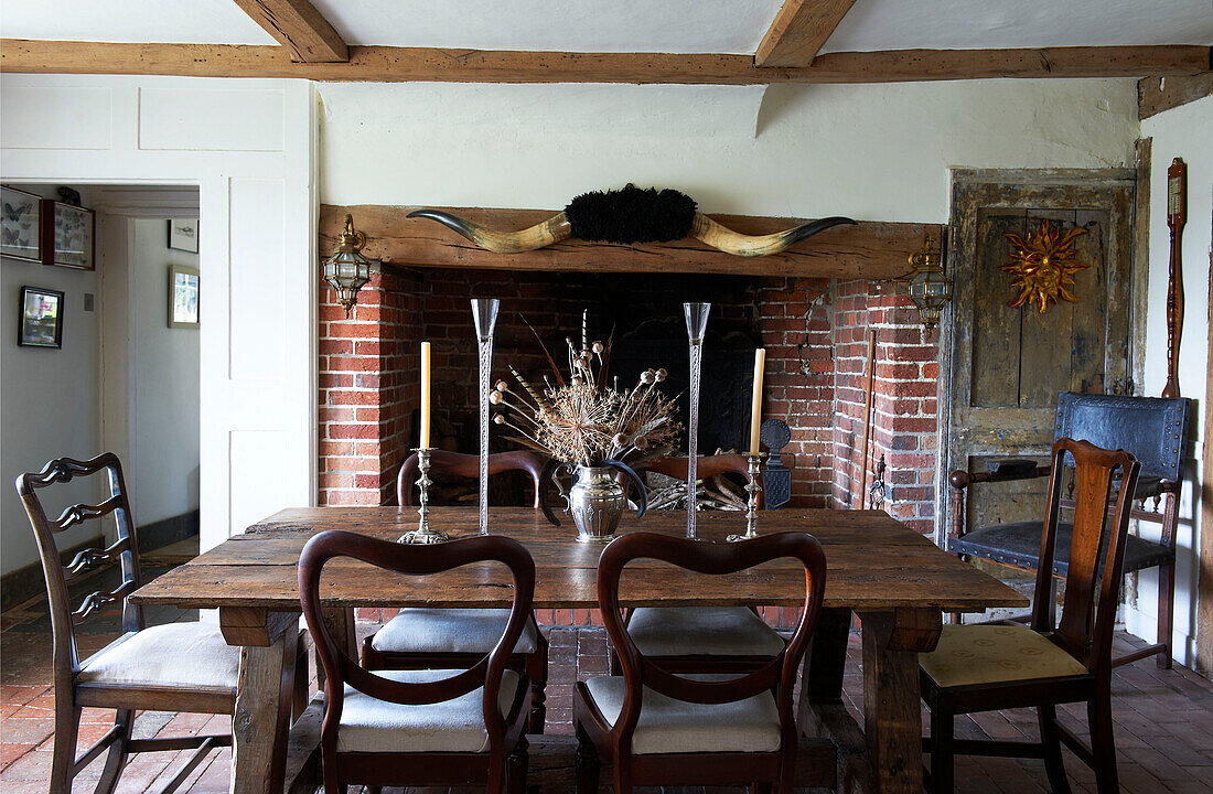 Antique dining table and exposed brick fireplace in Iden farmhouse, Rye, East Sussex, UK