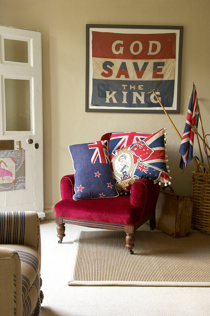 "God Save the King eingerahmt über rotem Samtsessel mit Union-Jack-Kissen in einem Haus in Suffolk, England, Vereinigtes Königreich"""
