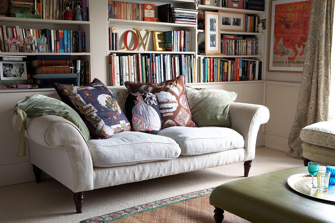 "Bücherregal mit Ornamenten und dem Wort love"" über einem Zweisitzer-Sofa in einem Haus in Suffolk, England, UK"""