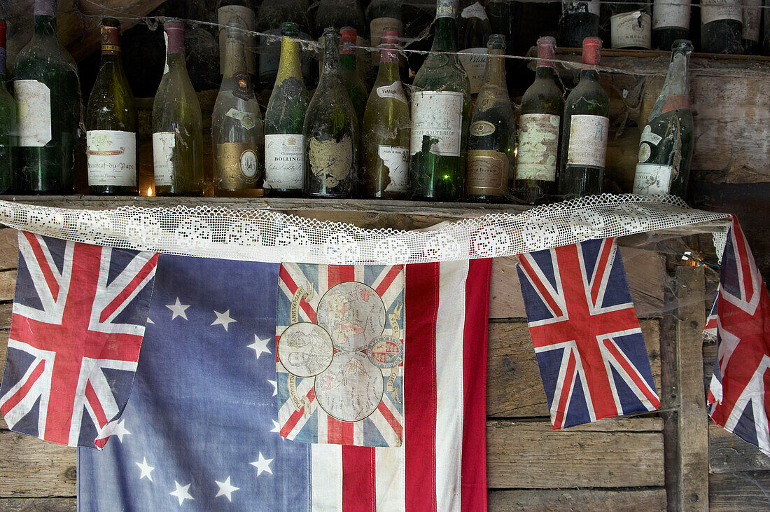 Verstaubte Weinflaschen über dem Union Jack im Gartenschuppen eines Hauses in Suffolk, England, UK