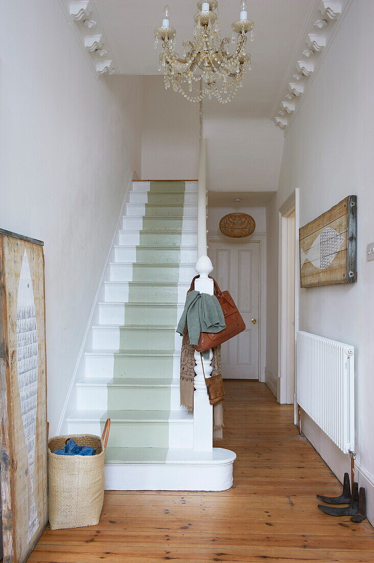 Painted staircase and chandelier in hallway with cornicing in Broadstairs home, Kent, England, UK