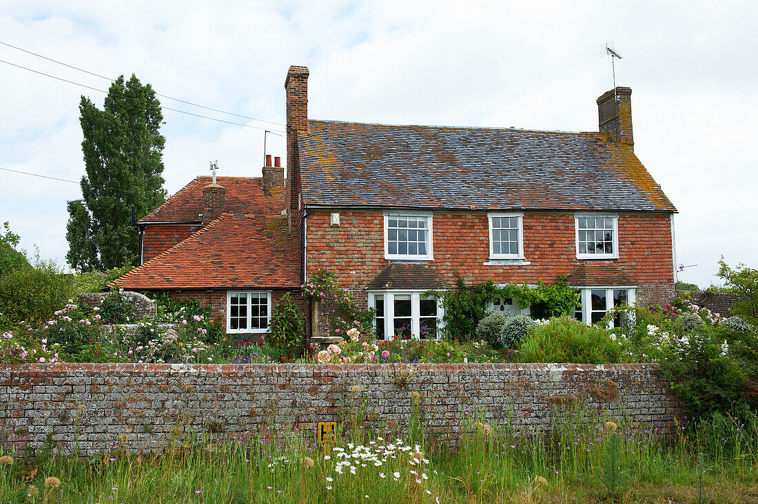 Backsteinmauer und Garten eines Cottages in Iden, Rye, East Sussex, Vereinigtes Königreich