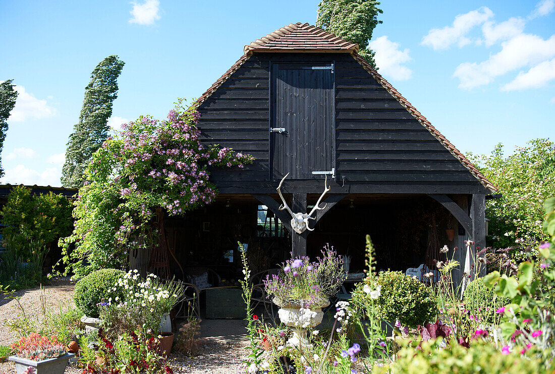 Creosote farm building in garden, Iden, Rye, East Sussex, UK
