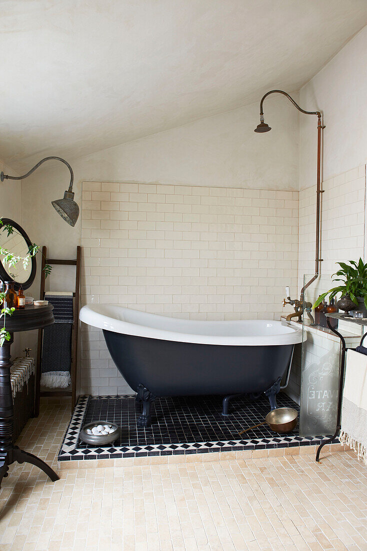 Freestanding bath with vintage shower head in tiled bathroom of Hastings cottage, East Sussex, England, UK