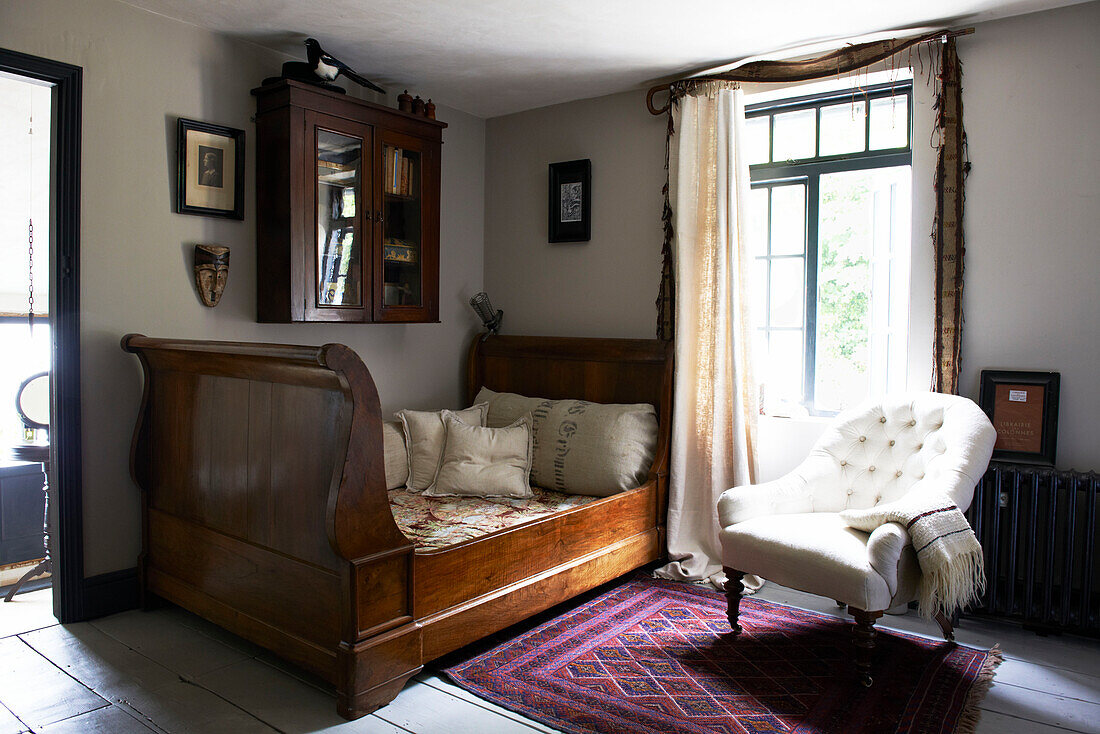 Poliertes Holzschlittenbett unter Wandschrank am offenen Fenster in einem Landhaus in Hastings, East Sussex, England, UK