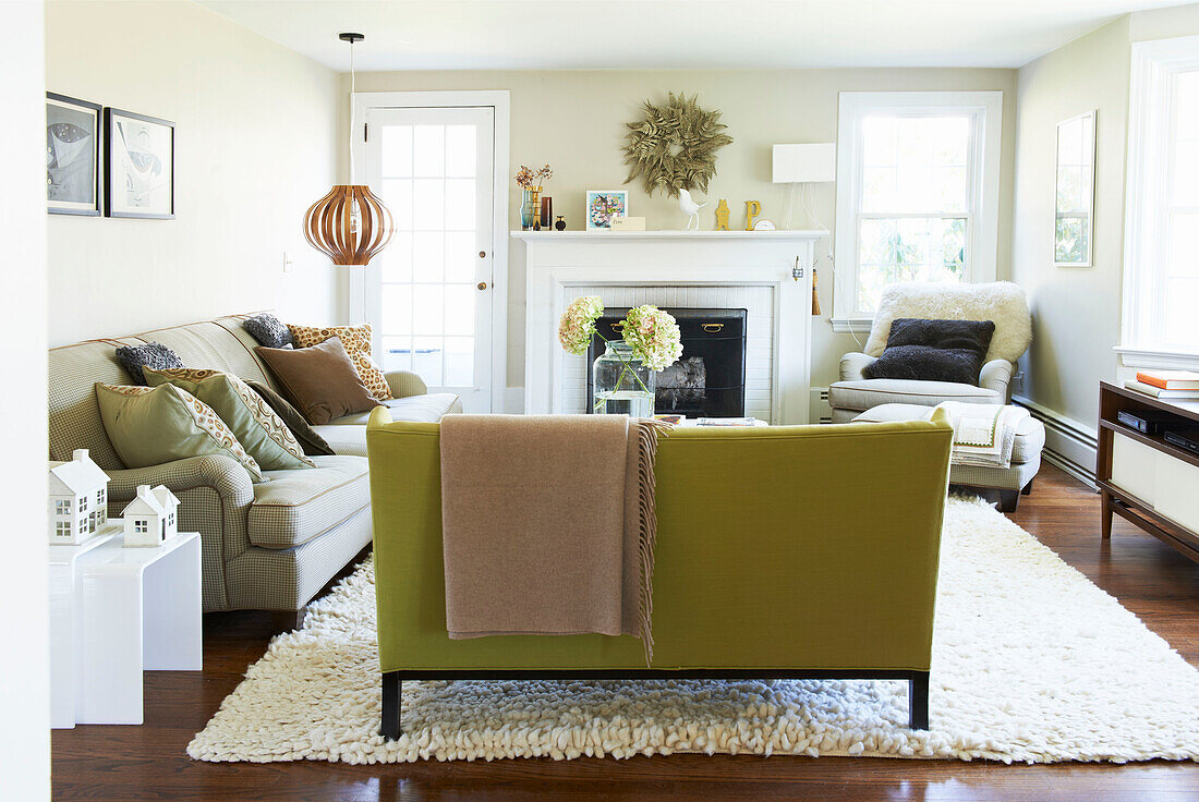 Beigefarbene Decke auf lindgrünem Sofa mit hölzerner Pendelleuchte in einem Wohnzimmer in den Berkshires, Massachusetts, Connecticut, USA