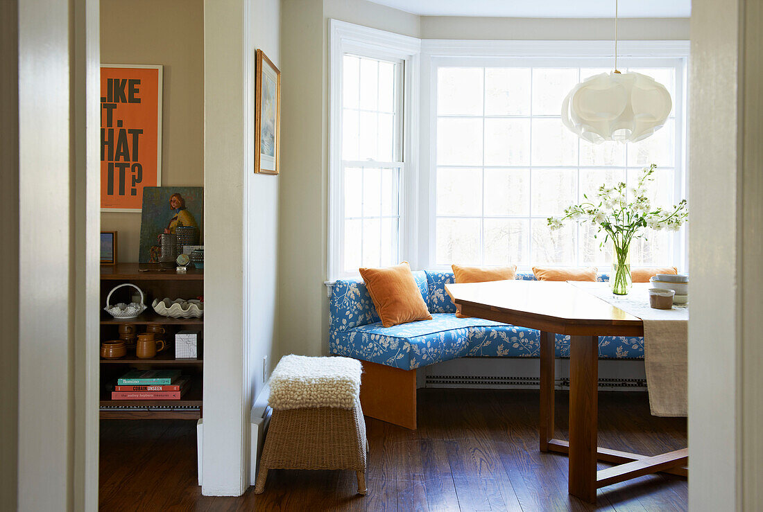 Orange velvet cushions on blue patterned window seat with wooden table in Berkshires home, Massachusetts, Connecticut, USA