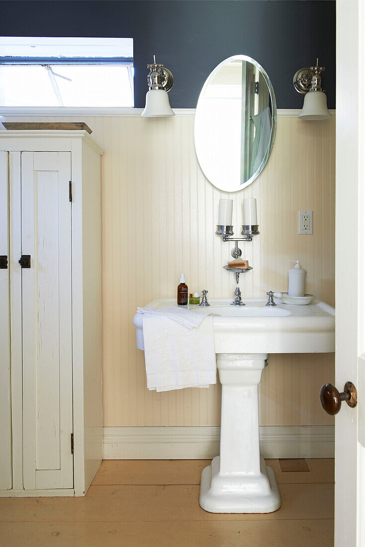 Ovaler Spiegel über einem Sockelbecken im getäfelten Badezimmer des Hauses in Austerlitz, Columbia County, New York, Vereinigte Staaten