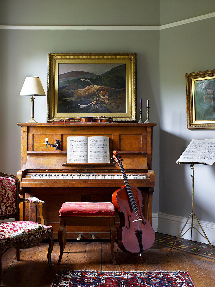 Cello lehnt auf Klavierhocker mit Notenblättern in Hereford, England, UK