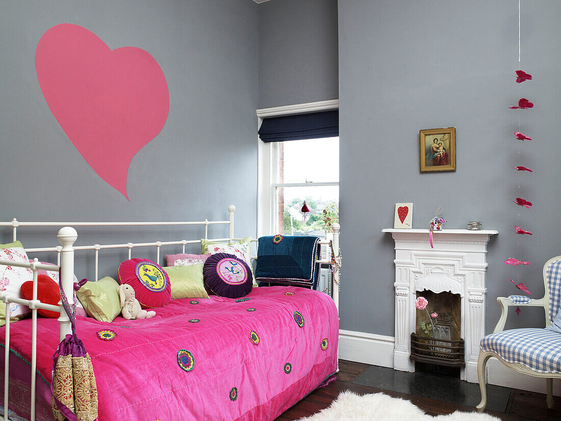Tintenherz auf grauer Wand eines Mädchenschlafzimmers mit Tagesbett und originalem Kamin in einem Haus in Hereford, England, UK
