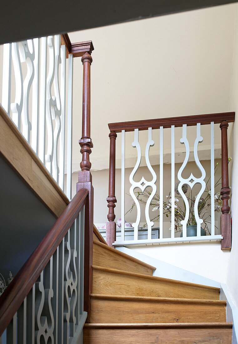 Ornate banister on wooden staircase with brown paintwork in Gloucestershire farmhouse, England, UK