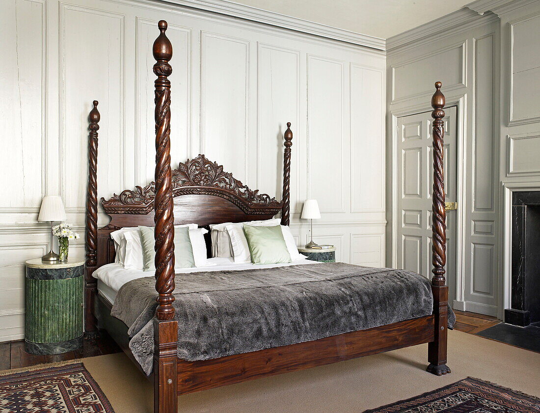 Carved wooden four poster bed in bedroom of Georgian townhouse, Laughame, Wales, UK