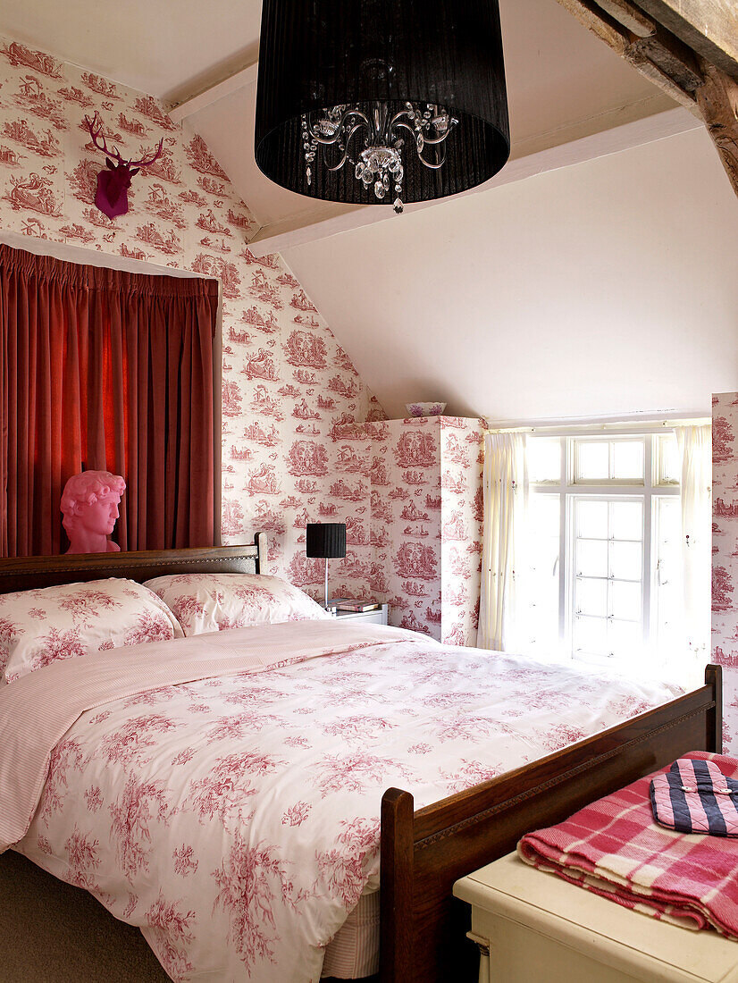 Toile de Jouy wallpaper and patterned duvet on bed in Welsh cottage, UK