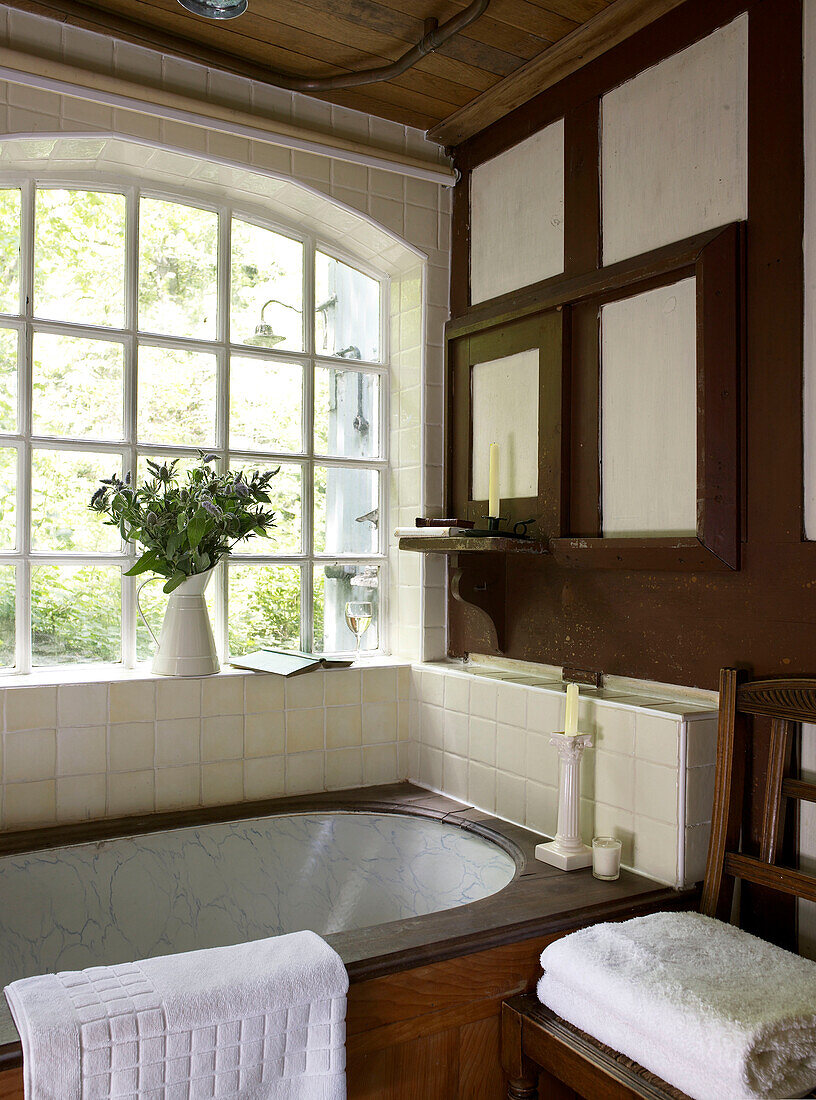 Badewanne am Fenster in einem Raum mit braunem Anstrich in einer umgebauten Kapelle in Shropshire, England, UK