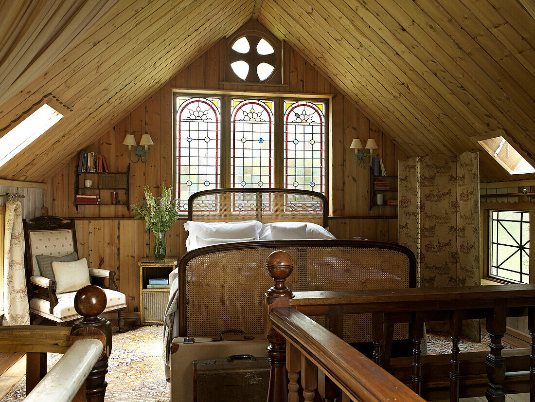 Rattanbett unter Glasfenster in umgebauter Kapelle in Shropshire, England, UK