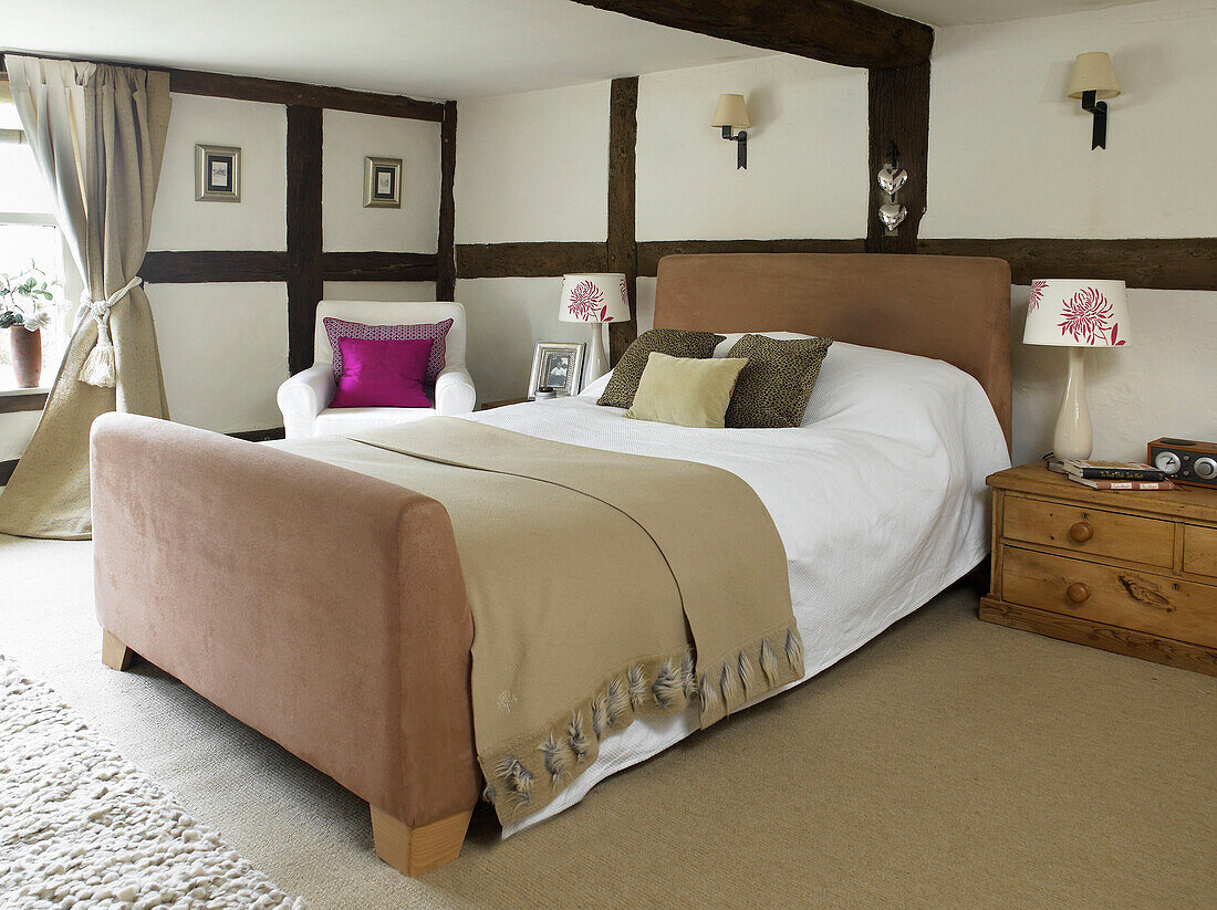 Double bed with woollen blanket in timber framed bedroom of Gloucestershire farmhouse England UK