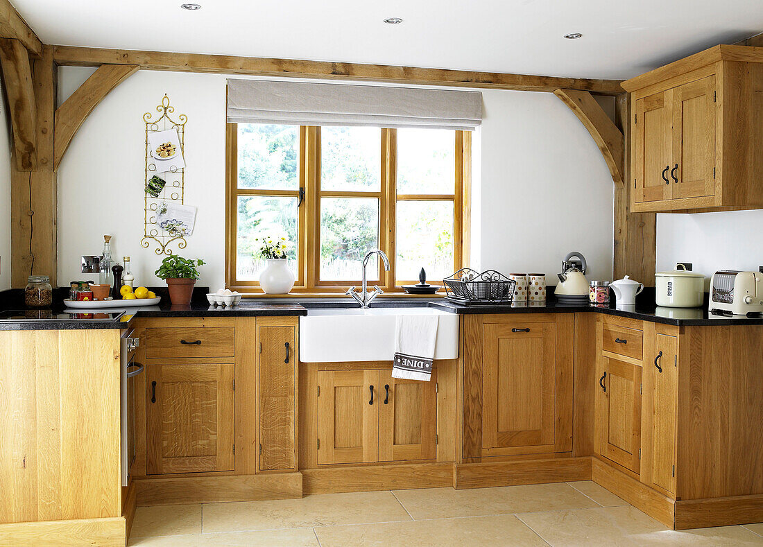 Wood fitted units at window in kitchen of Gloucestershire cottage England UK