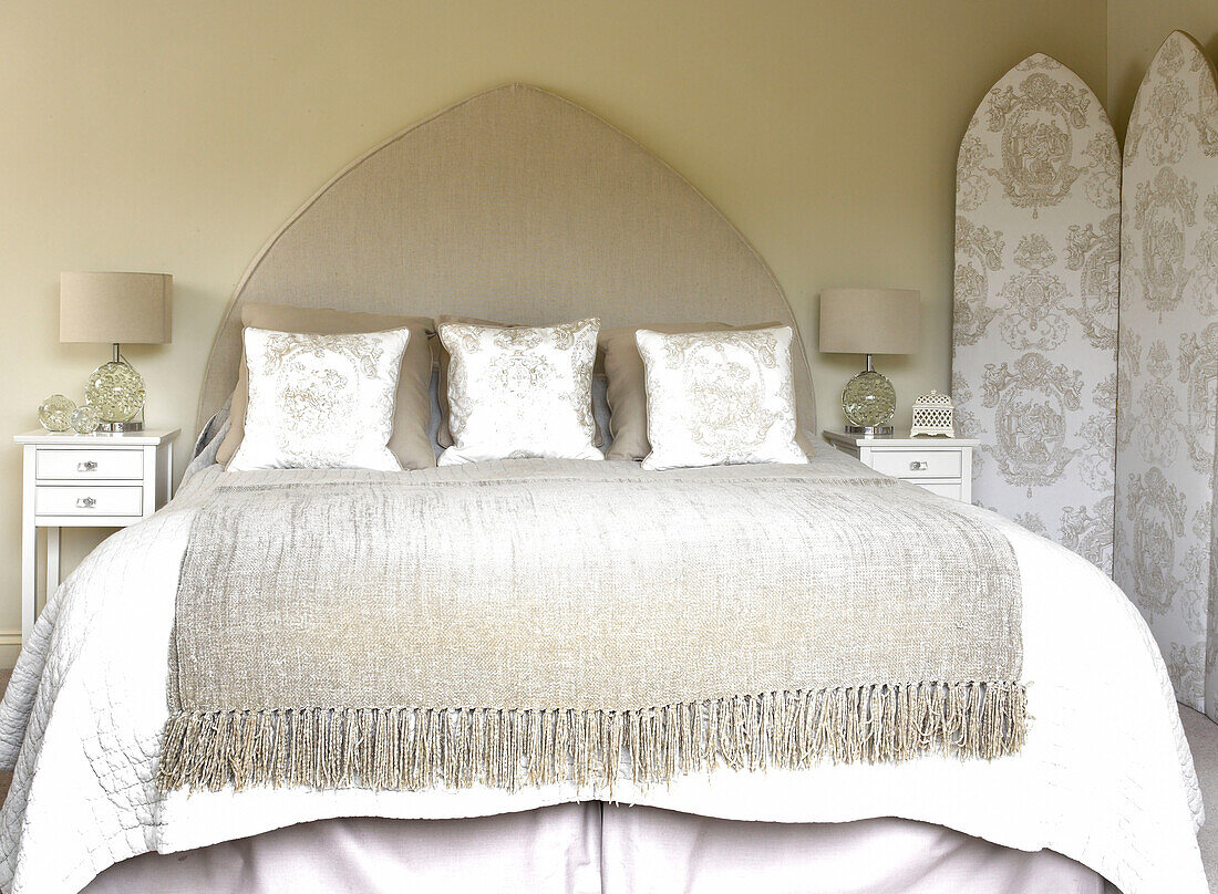 Gefaltete Decke auf Bett mit Spitzbogen-Kopfteil und passenden Kissen und Faltwand Somerset, Neubau, ländliches England, UK