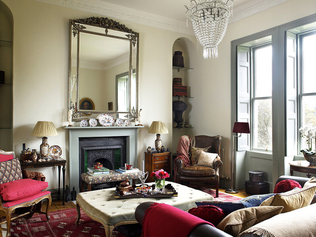 Ottoman at fireplace with antique mirror in living room of city of Bath home Somerset, UK