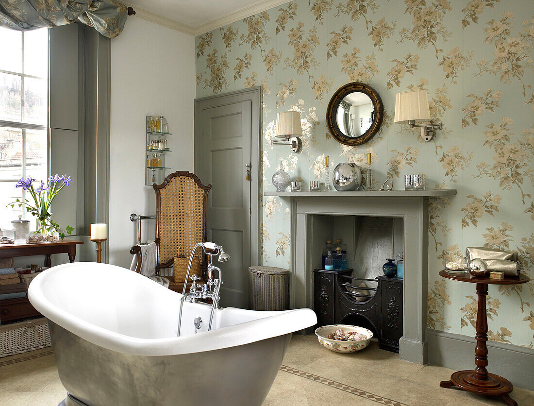 Freistehende Badewanne und Blumentapete mit grauem Anstrich in einem Badezimmer in Bath, Somerset, UK
