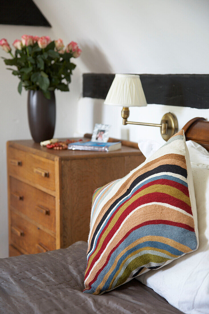 Striped cushion on bed with roses on bedside city of Bath Somerset, UK