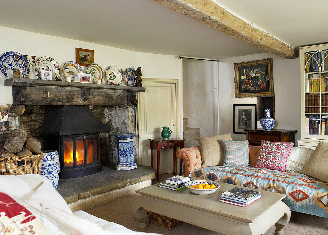 Fireplace with decorative chinaware in living room of Gloucestershire cottage, England, UK