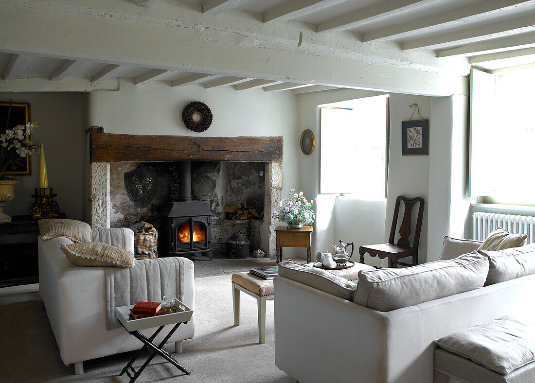 Weiße Sofas und Kaminofen im Wohnzimmer eines Hauses in Gloucestershire, England, UK