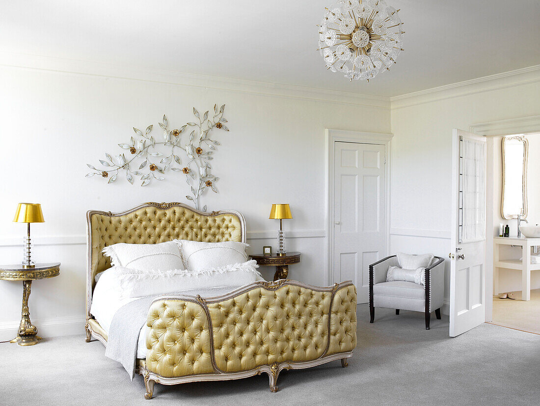 Vintage Deckenleuchte mit dekorativem Blattmotiv und mit goldfarbenem Stoff gepolstertes Bett, in einem Haus in Bath, Somerset, England, UK