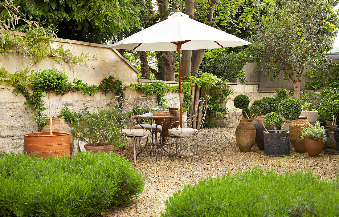 Outdoor seating and parasol in walled garden in city of Bath, Somerset, England, UK