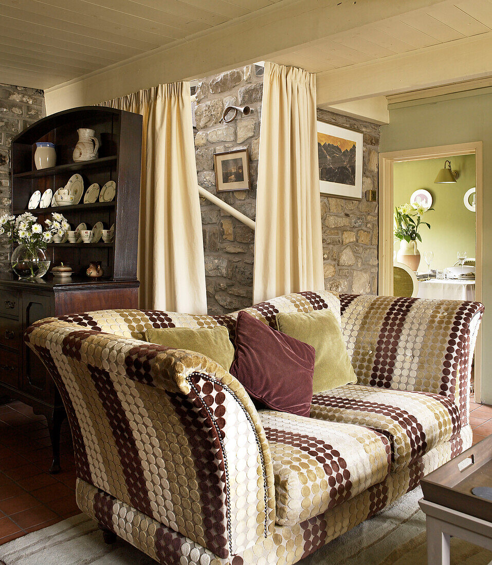Upholstered sofa and kitchen dresser in living room of Welsh cottage, UK