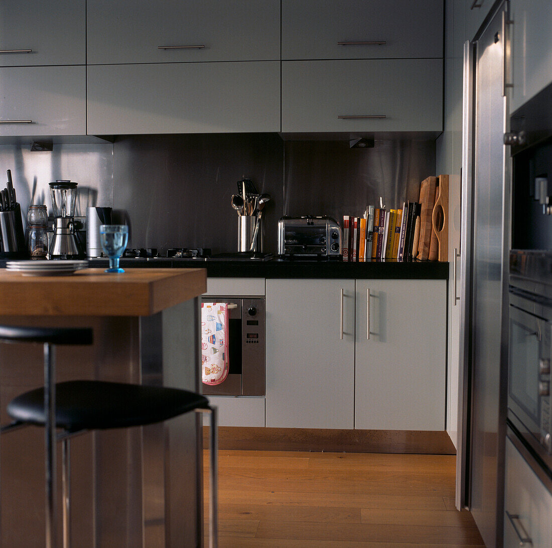 Moderne Küche aus rostfreiem Stahl und grauem Anstrich mit Frühstücksbar, Holzböden und viel Stauraum