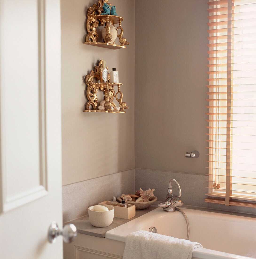 Modernes neutrales Badezimmer mit goldenen Regalen und Toilettenartikeln