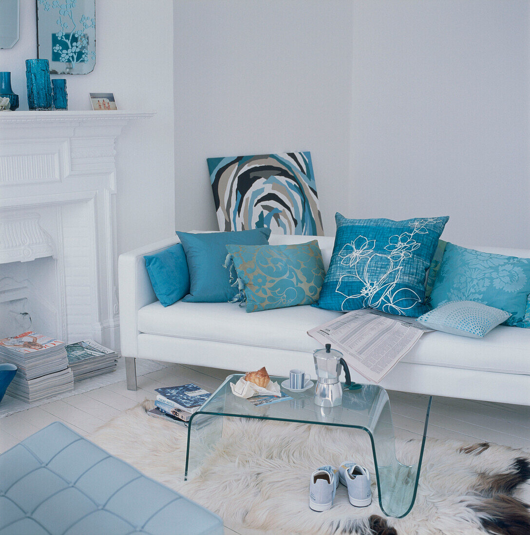 Zeitgenössisches Wohnzimmer mit weiß gestrichenen Dielenböden, weißem Sofa und türkis-weißem Dekor