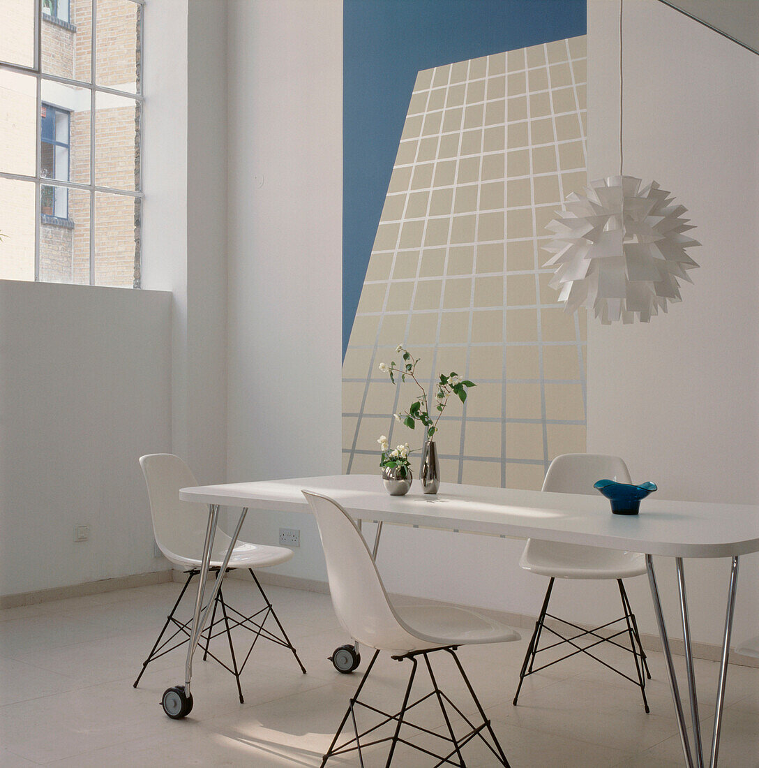 Zeitgenössisches Esszimmer mit Steinboden, weißem Esstisch und Stühlen sowie türkisem und weißem Dekor