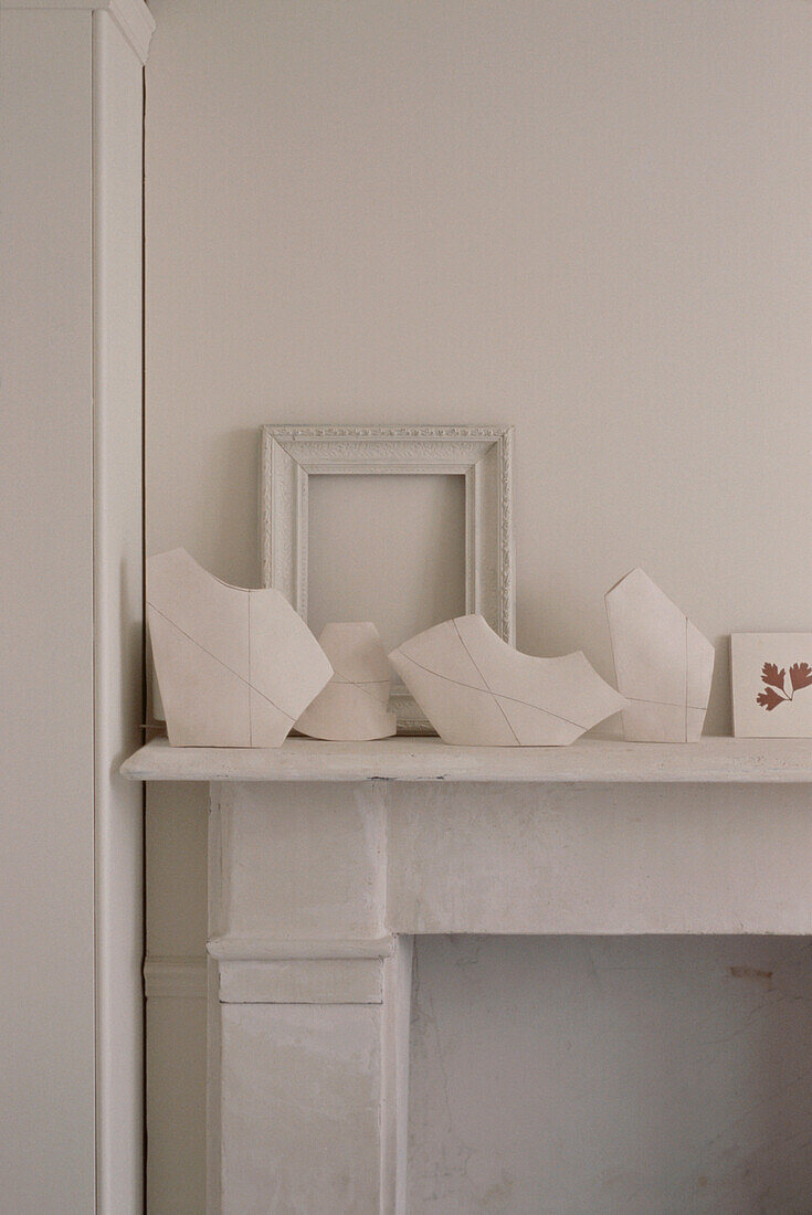 Auslage mit weißen Haushaltswaren auf einem weißen Kaminsims in einem Wohnzimmer