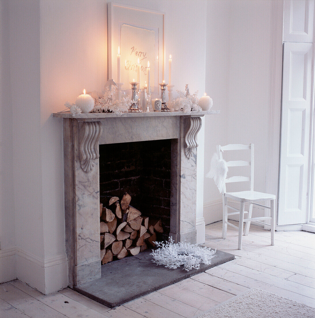 Kamin mit Weihnachtsdekoration und brennenden Kerzen in einem modernen weißen Wohnzimmer