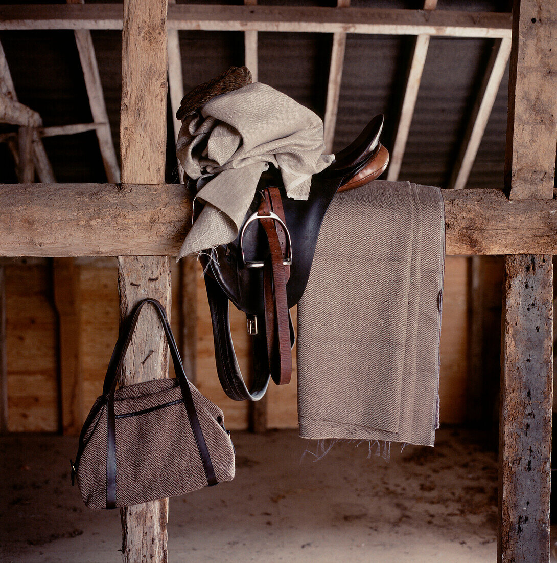 Horse riding equipment and blankets stored over beams in an old stable
