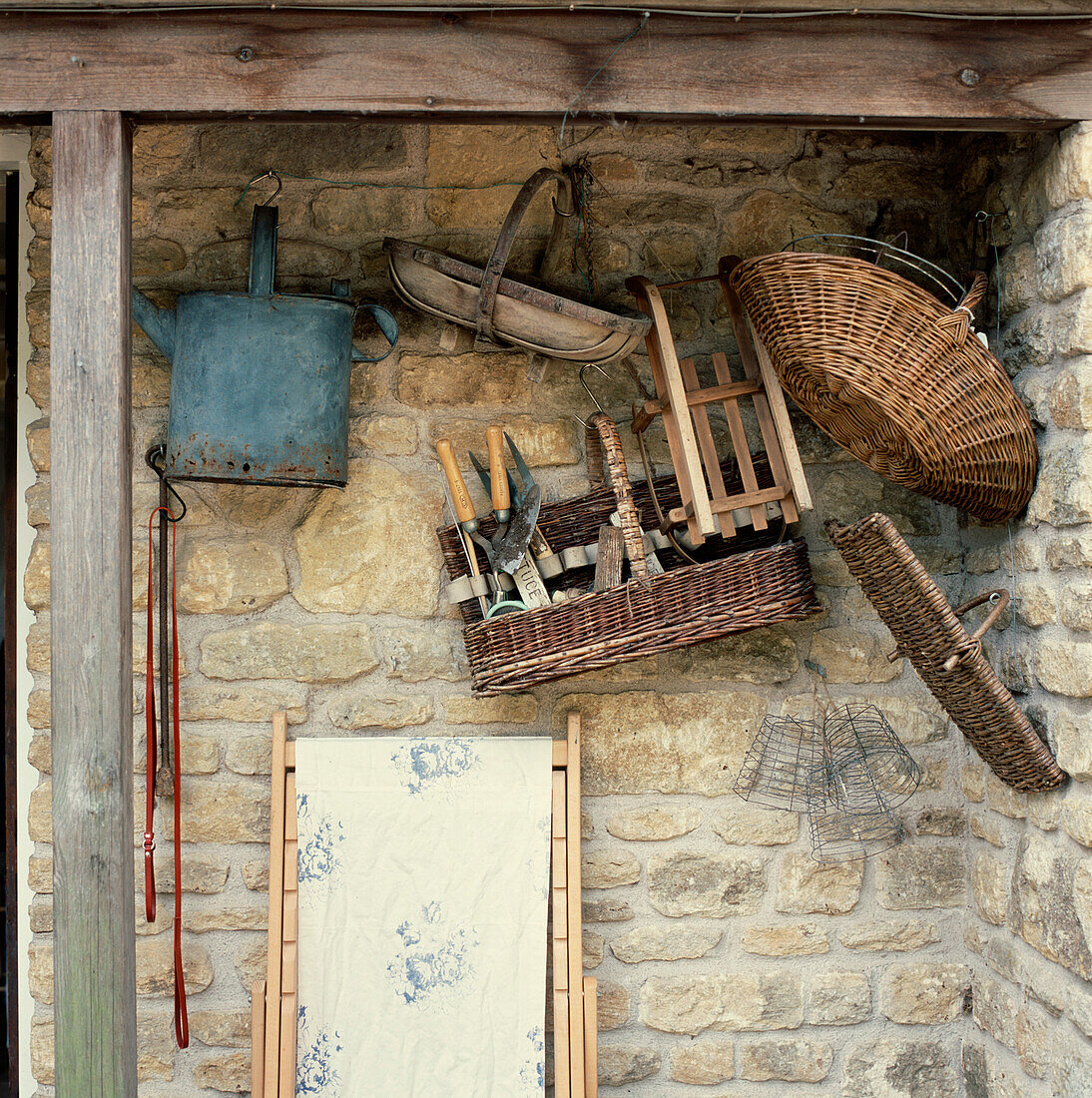 Stone walled shed with collection of gardening baskets and trugs hanging on the wall