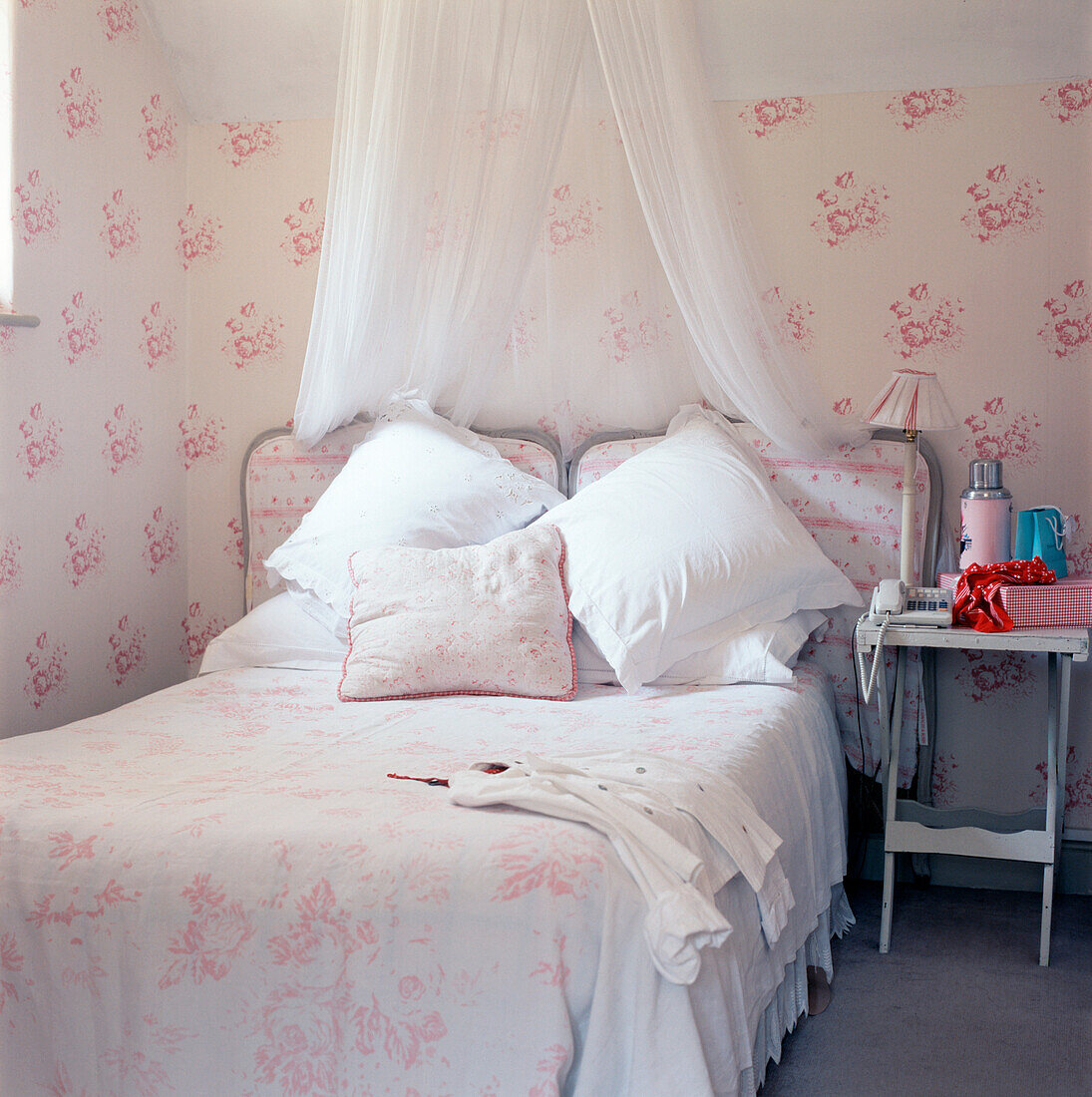 Feminines Doppelschlafzimmer mit Blumentapete und Bett mit Bettwäsche